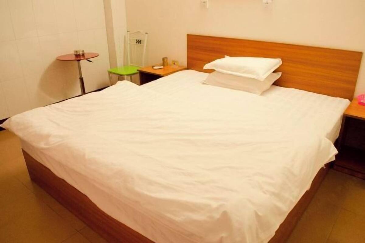 Una habitación de hotel con una cama grande, una mesita de noche, una silla y una pequeña mesa redonda.