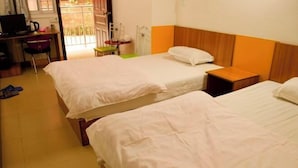 Une chambre d’hôtel avec deux lits, un bureau avec un ordinateur, une chaise et une petite table.