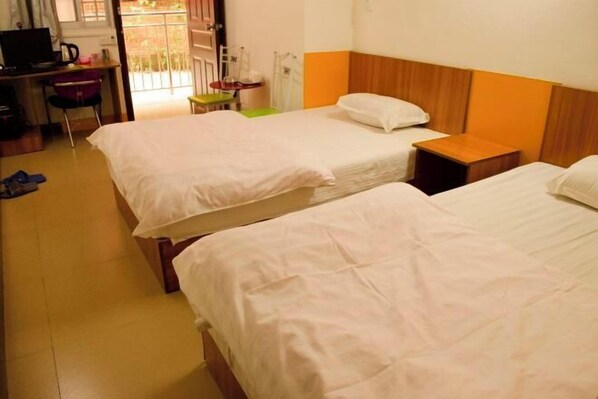 Habitación de hotel con dos camas, un escritorio con ordenador, una silla y una mesita.
