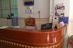 Un mostrador de recepción con una computadora, un dispensador de agua y un cartel con texto.