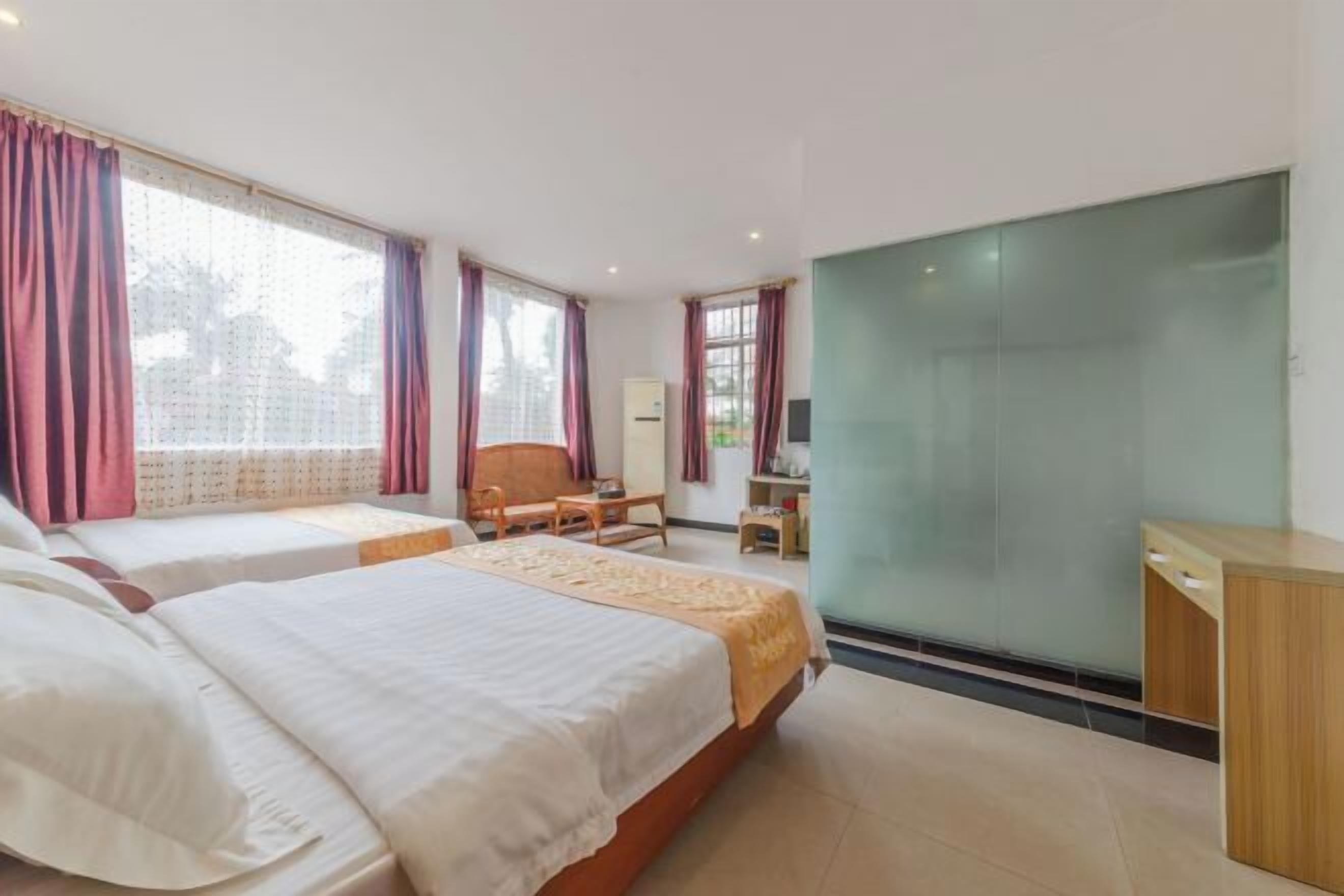 A hotel room with two beds, a desk, a chair, and a large mirror.