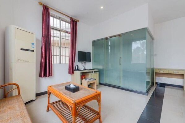 A compact room with a bed, a small table, a TV, and a wardrobe. - Tingtaoju Hotel (Taishan)