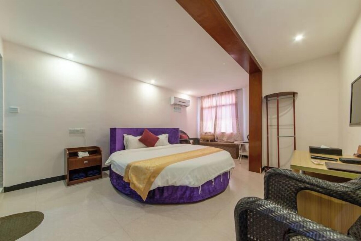 A hotel room with a bed, a desk, a chair, and a wardrobe.