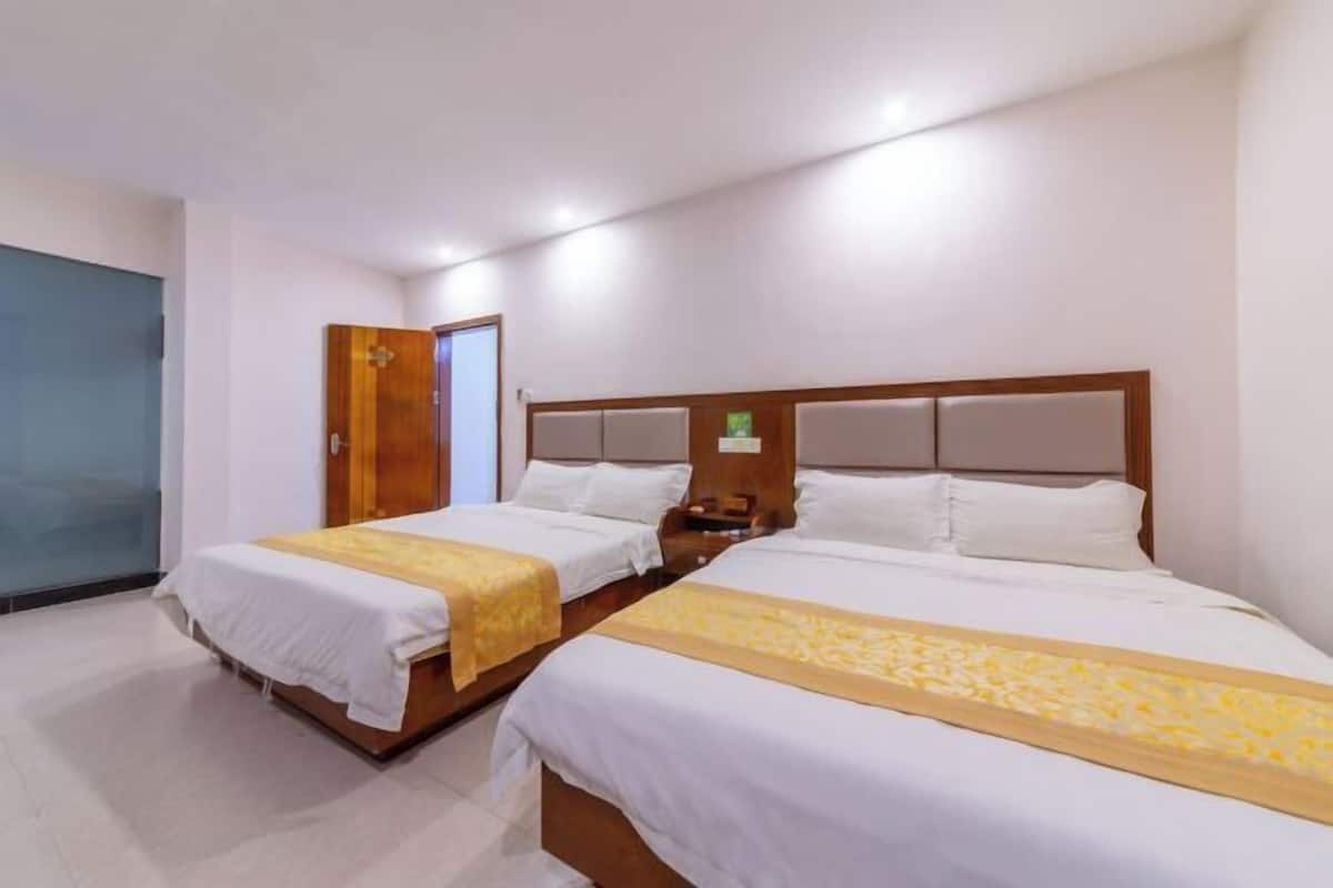A hotel room with two beds, a wooden headboard, a nightstand, and a door.