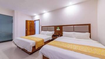 A hotel room with two beds, a wooden headboard, a nightstand, and a door.