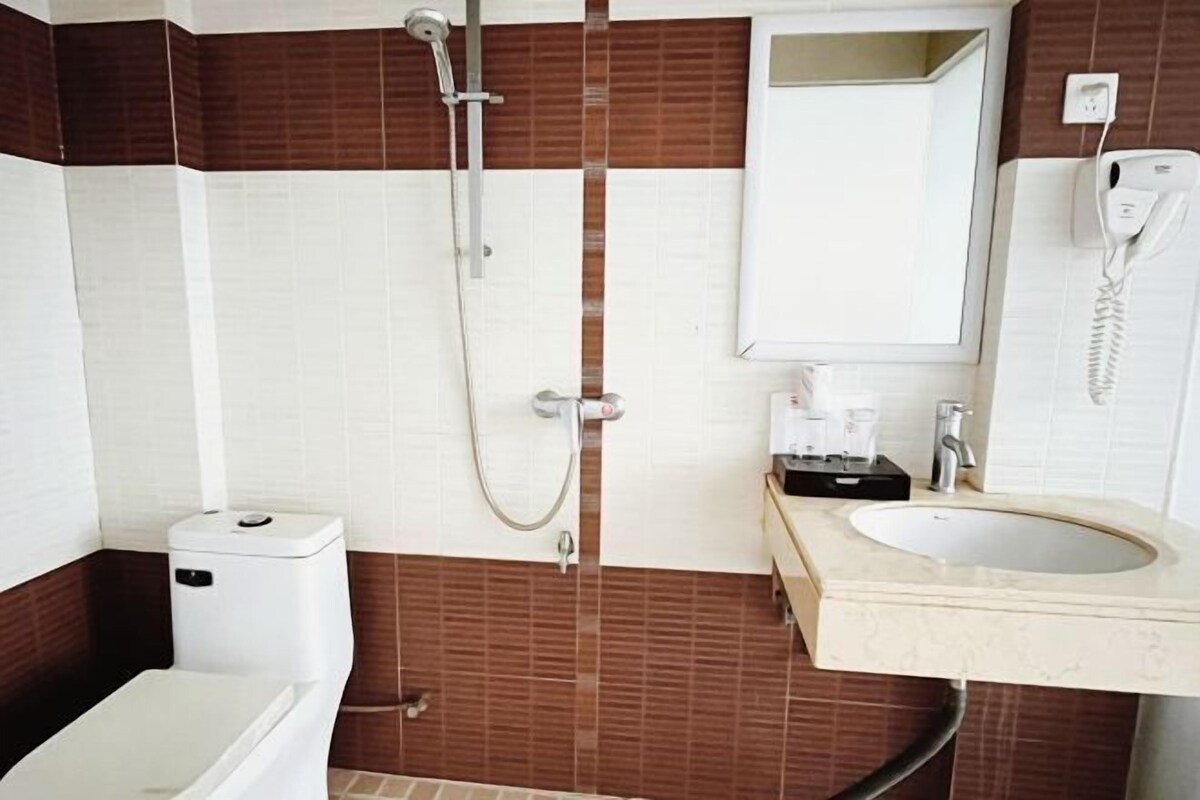 A bathroom with a toilet, a shower, a sink, and a mirror.