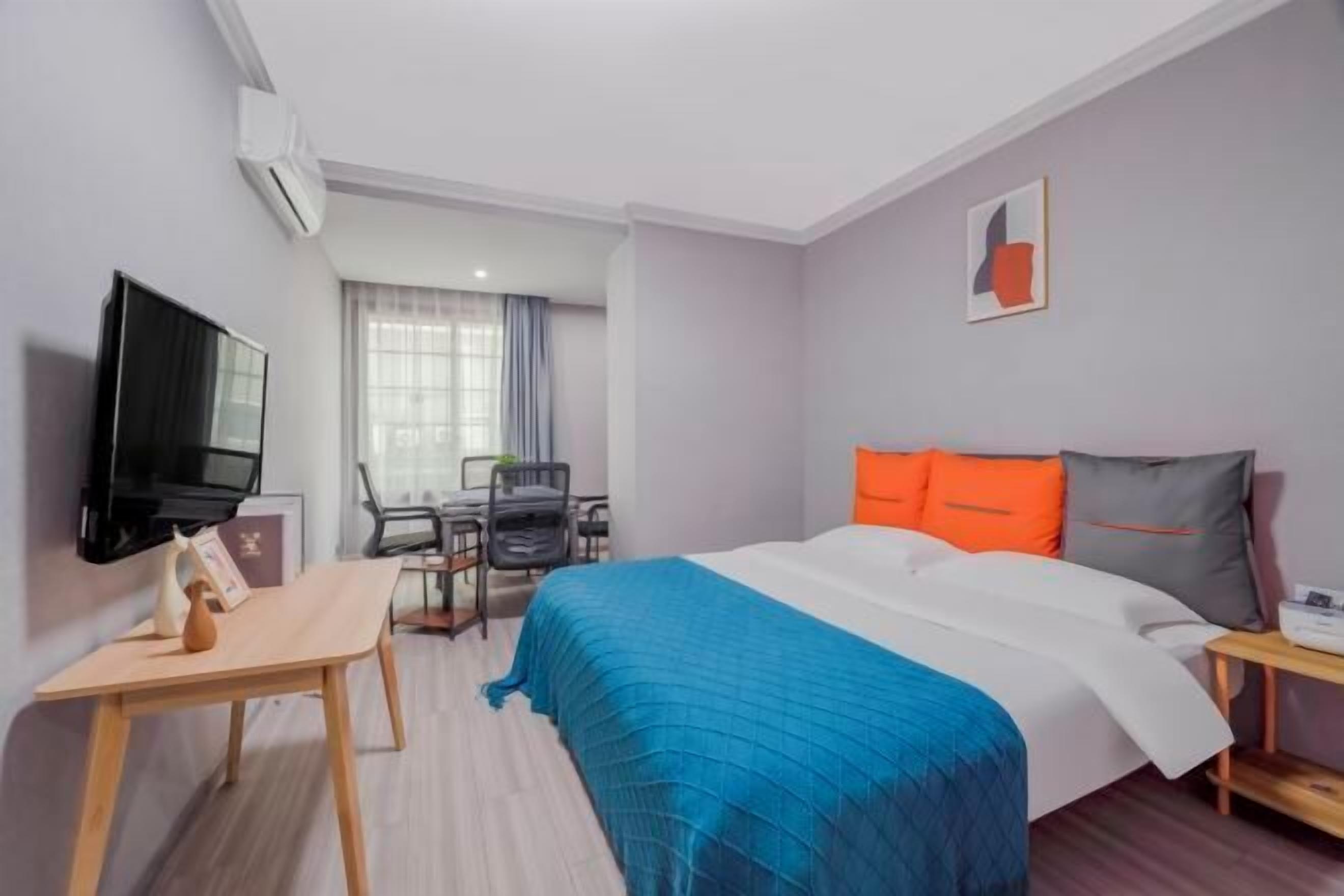 Une chambre d’hôtel avec un lit, un bureau, une chaise, une télévision et une fenêtre avec des rideaux.