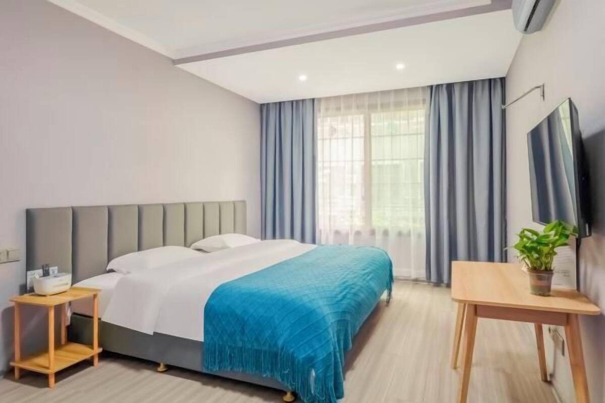 Une chambre d’hôtel moderne équipée d’un lit, d’une table de chevet et d’un téléviseur.