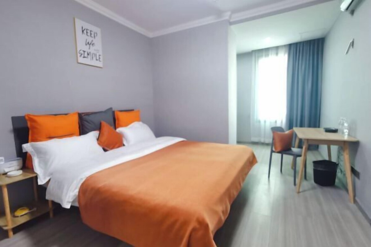 A hotel room with a bed, a desk, a chair, and a small table.