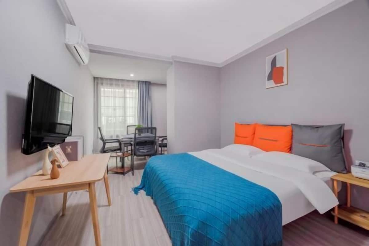 Une chambre d’hôtel avec un lit, un bureau, une chaise, une télévision et une fenêtre.