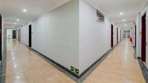 A long, narrow hotel corridor with white walls, red doors, and a shiny floor. - Muxi City Hotel (Hengyang Jiefang Road) (Hengyang)