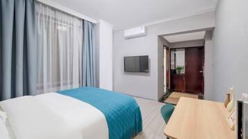 Una habitación de hotel con una cama, un escritorio, un televisor y una puerta que da a otra habitación.