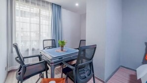 A small, modern room with a dining table and four chairs, a potted plant on the table, and a window with sheer curtains. - Muxi City Hotel (Hengyang Jiefang Road) (Hengyang)