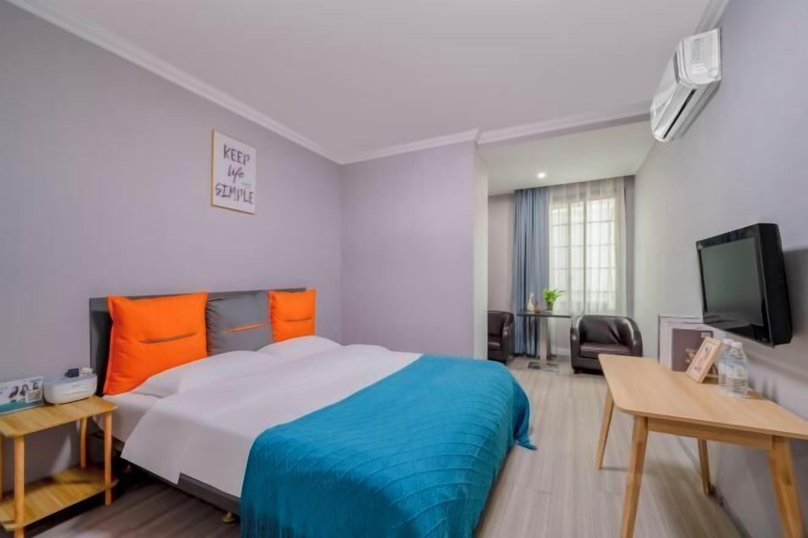 Una habitación de hotel con cama, escritorio, televisor y aire acondicionado.
