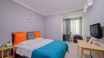 Una habitación de hotel con cama, escritorio, televisor y aire acondicionado.