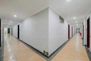 Un pasillo largo y estrecho con puertas a ambos lados, piso de baldosas y una rejilla en la pared.
