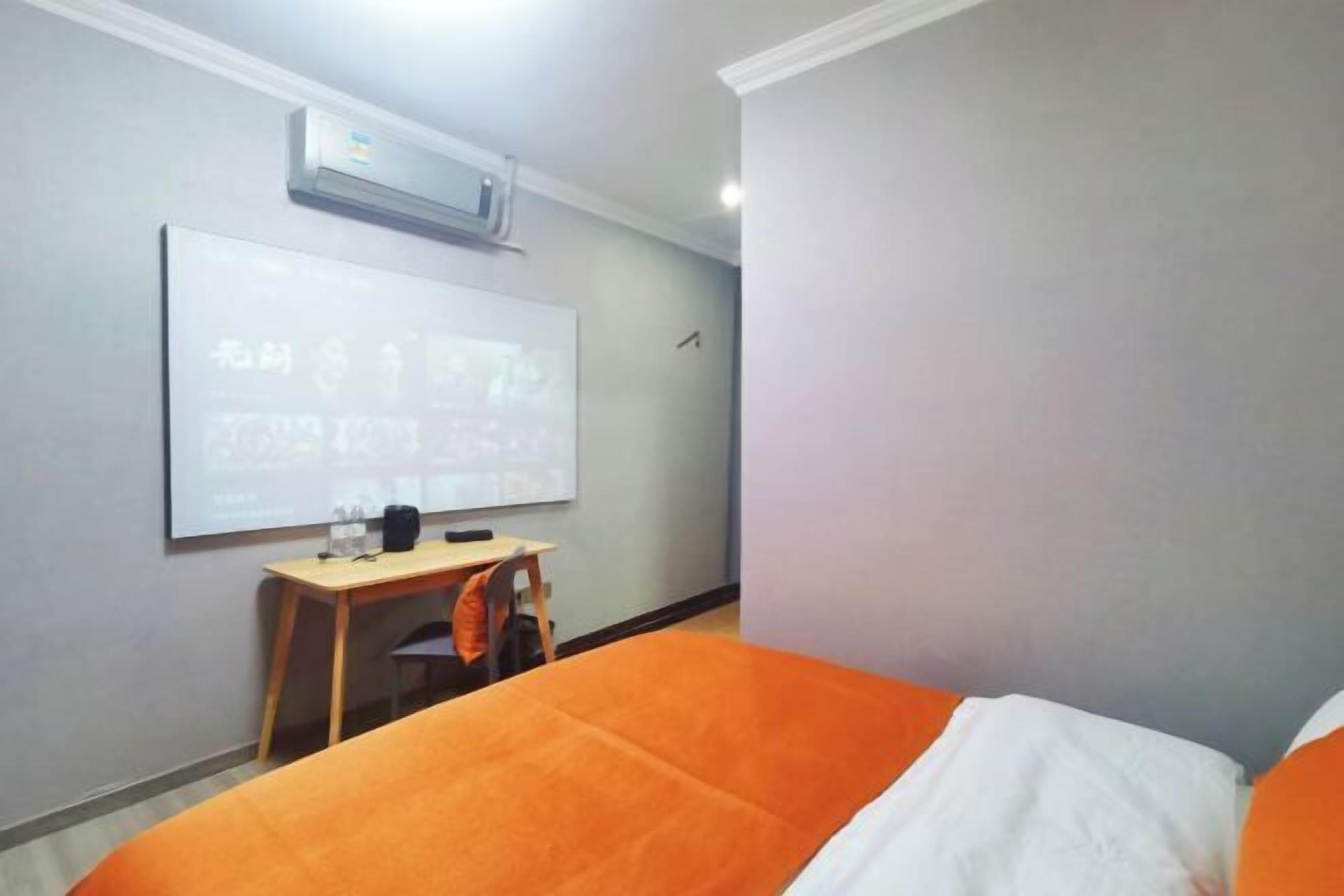 A hotel room with a bed, a desk, and a whiteboard on the wall.