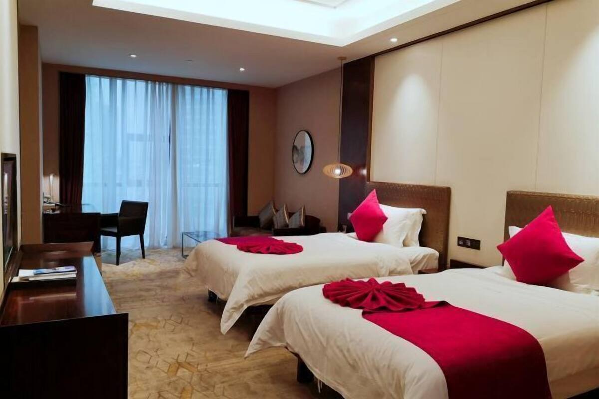 A hotel room with two beds, a desk, and a chair.