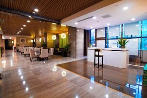 Un hall de hotel con mostrador de recepción, zona de estar y grandes ventanales.