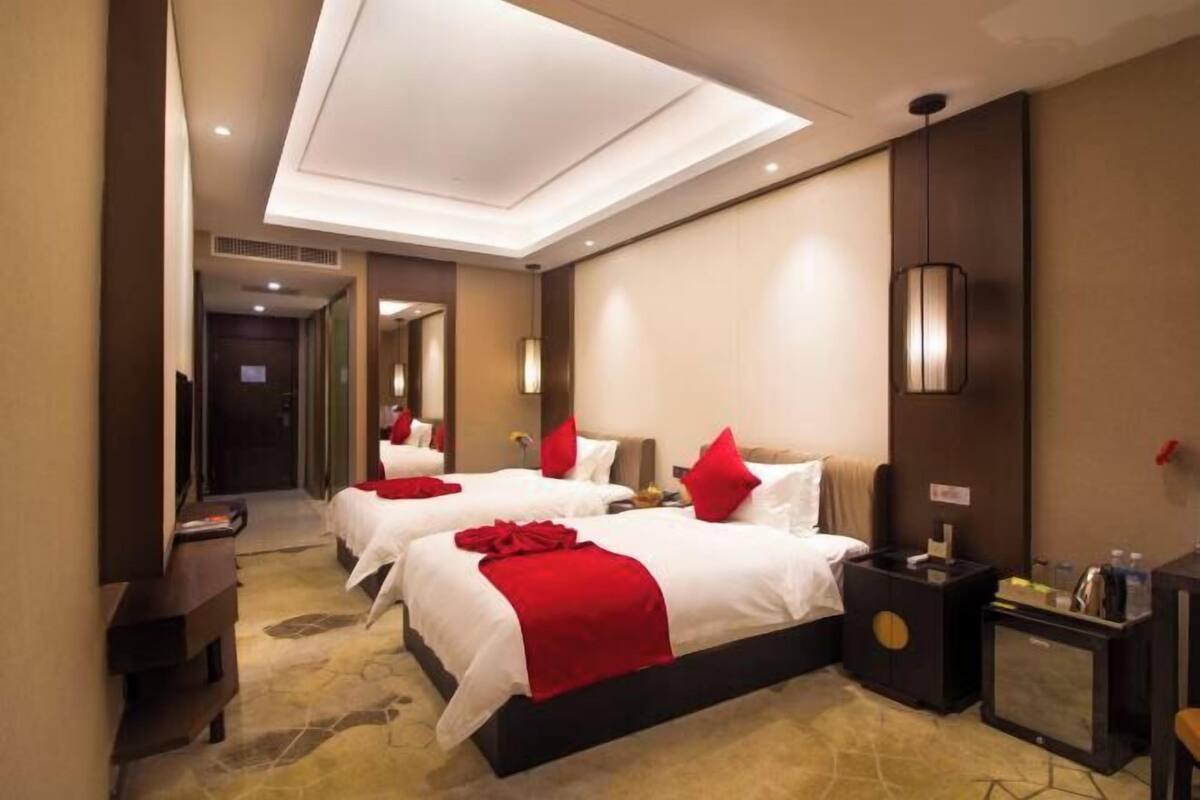 A hotel room with two beds, a desk, a TV, and a minibar.