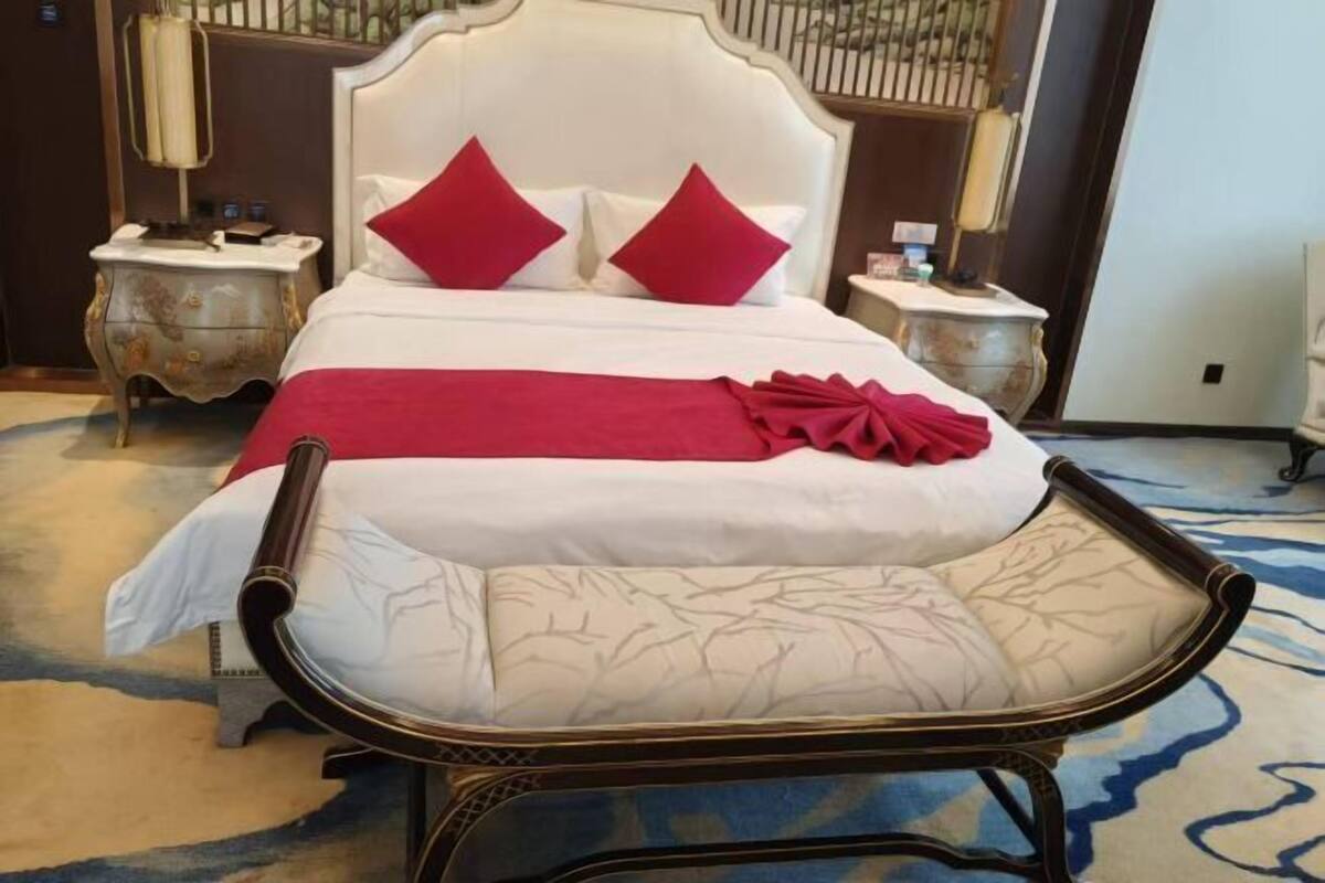 A hotel room with a large bed, two nightstands, a chair, and a decorative mirror.