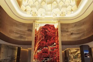 Un vestíbulo con un mural grande e iluminado, un diseño moderno de techo y una zona de recepción.