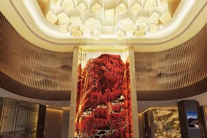 Un vestíbulo con un mural grande e iluminado, un diseño moderno de techo y una zona de recepción.