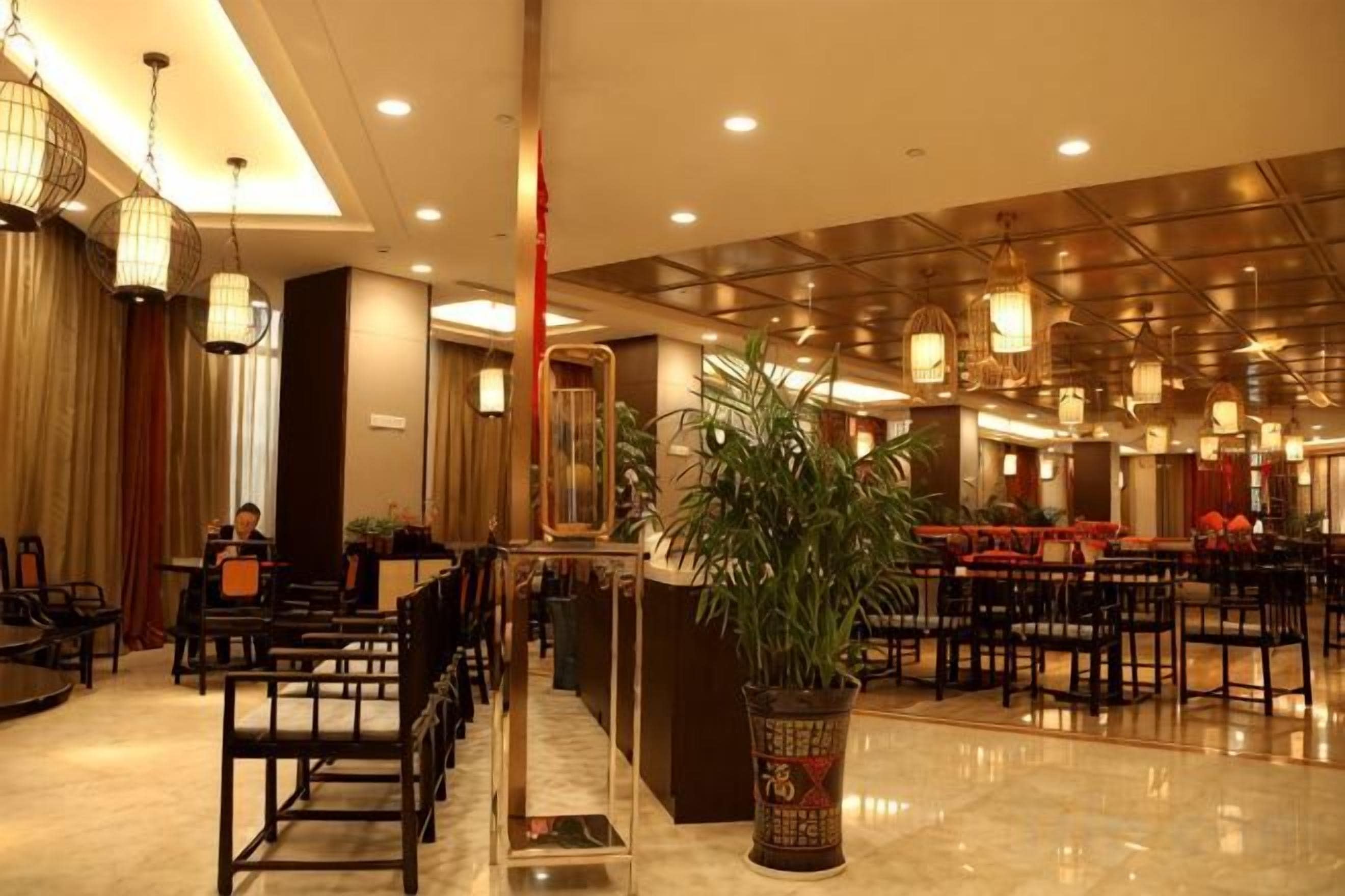 A hotel lobby with a reception desk, seating area, and a large potted plant.