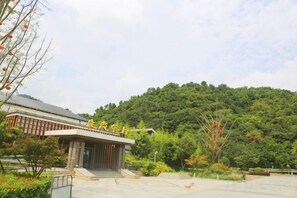 A building with a traditional architectural style, surrounded by greenery and a hilly landscape.