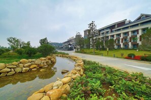 A residential building with a paved pathway, a small water feature with rocks, and greenery.