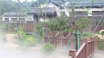 A traditional Japanese-style building with a wooden fence and greenery.