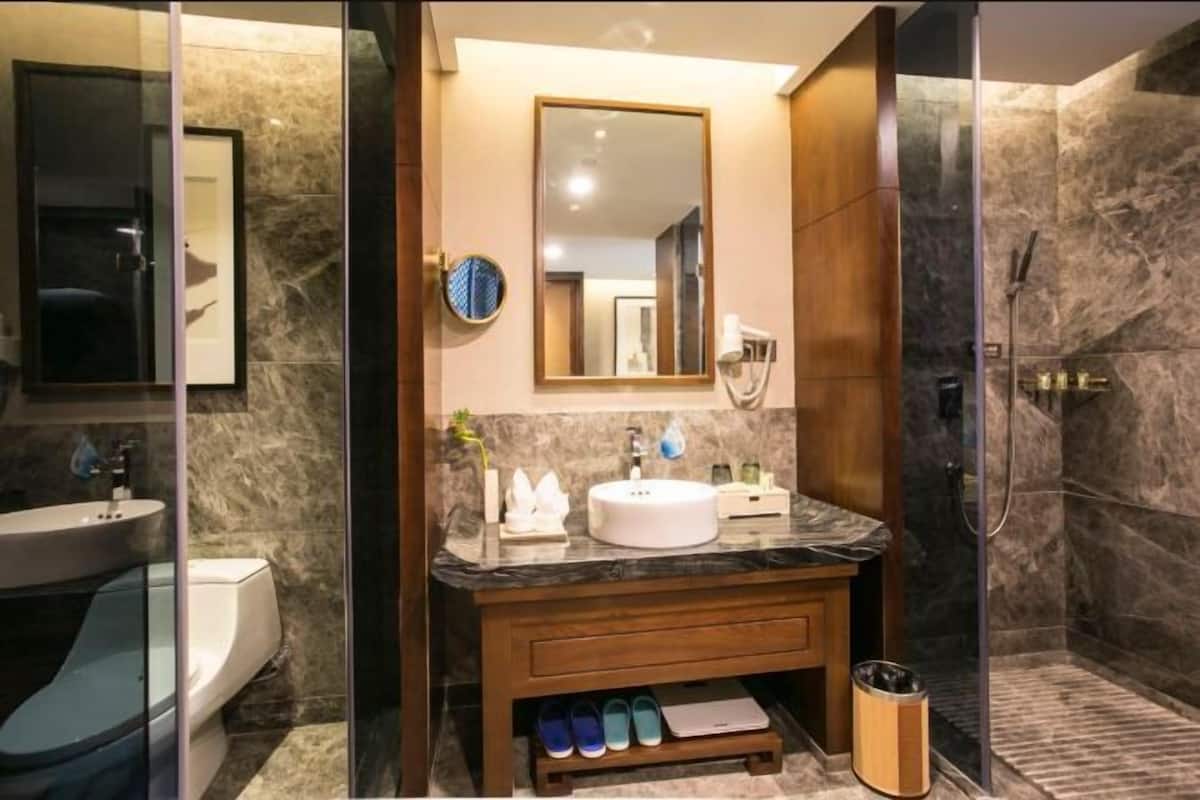 Casa de banho moderna com lavatório de mármore, um espelho grande e cabine de duche.