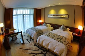 A hotel room with two beds, a desk, a chair, a large window with curtains, and a framed picture on the wall. - Chuishan Hot Spring Resort (Zhenjiang)