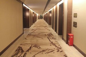 A hotel corridor with a patterned carpet, doors on both sides, and a red object on the right wall. - Chuishan Hot Spring Resort (Zhenjiang)
