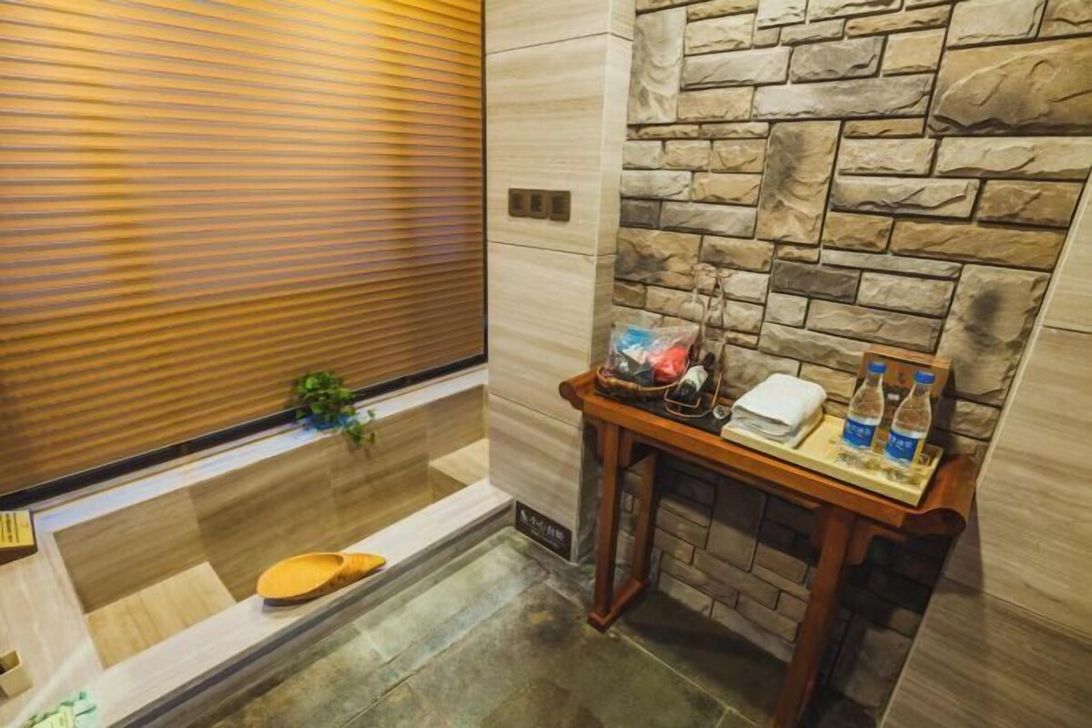 A bathroom with a stone wall, a wooden bench, and a small table with toiletries.