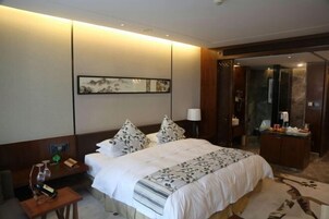 Una habitación de hotel con cama, mesita de noche, lámpara y un cuadro en la pared.