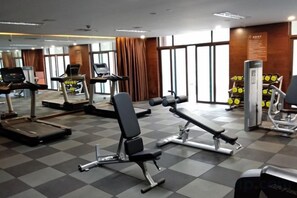 A gym with exercise equipment including treadmills, a bench press, and weight machines.