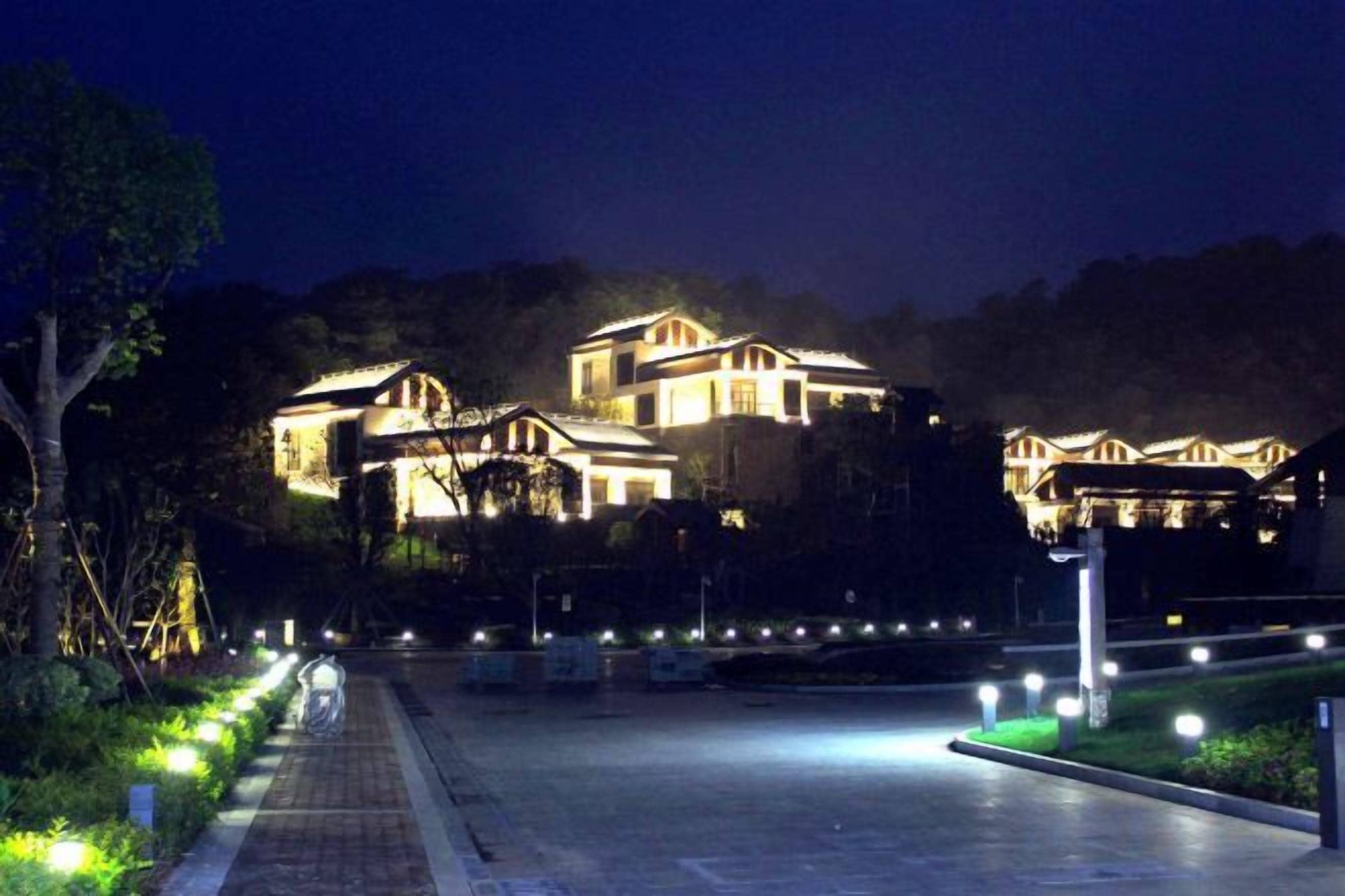 A well-lit building with multiple levels, surrounded by a paved area with lights.