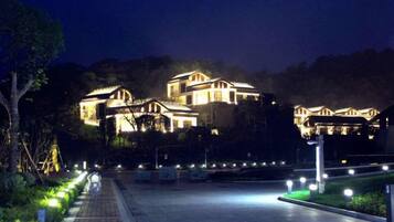 A well-lit building with multiple levels, surrounded by a paved area with lights.