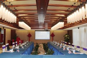 A conference room with a long table, microphones, and a screen at the front.