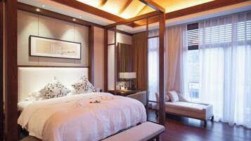 Een slaapkamer met een groot bed, nachtkastje, bankje en uitzicht buiten door gordijnen.