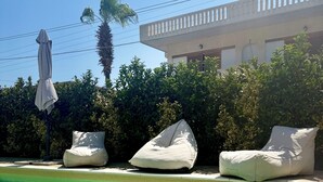 Een helder zwembad met drie loungestoelen en een parasol.