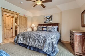 Une chambre à coucher avec un lit, une armoire en bois et un ventilateur de plafond.
