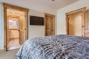 Ein Schlafzimmer mit einem großen Bett, einem Holzschrank und einem Fernseher an der Wand.