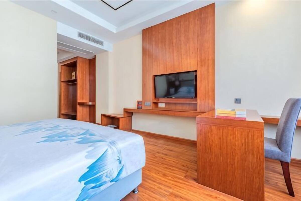 A hotel room with a bed, a desk, a TV, and a wardrobe.