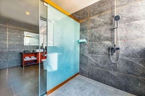 Une salle de bain moderne avec une douche à parois de verre, un mur recouvert de carreaux de marbre et un meuble-lavabo rouge.