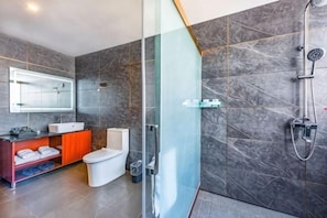 Une salle de bain moderne avec une douche à parois de verre, des toilettes blanches et un meuble-lavabo avec un miroir.