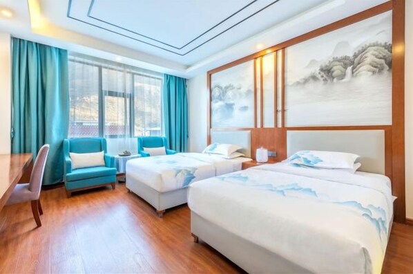 Une chambre d’hôtel avec deux lits, un bureau, une chaise et un grand tableau au mur.
