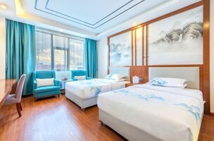A hotel room with two beds, a desk, a chair, and a large painting on the wall.