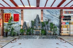 A lobby with a marble floor, a rock garden centerpiece, and red banners.